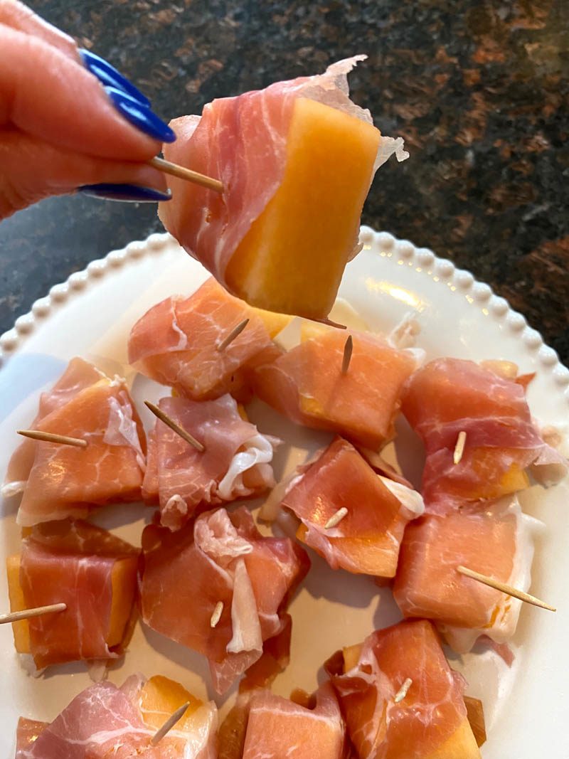 Prosciutto wrapped cantaloupe on a plate.