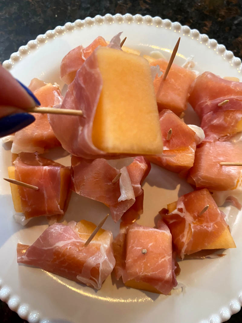 Prosciutto wrapped cantaloupe on a plate.