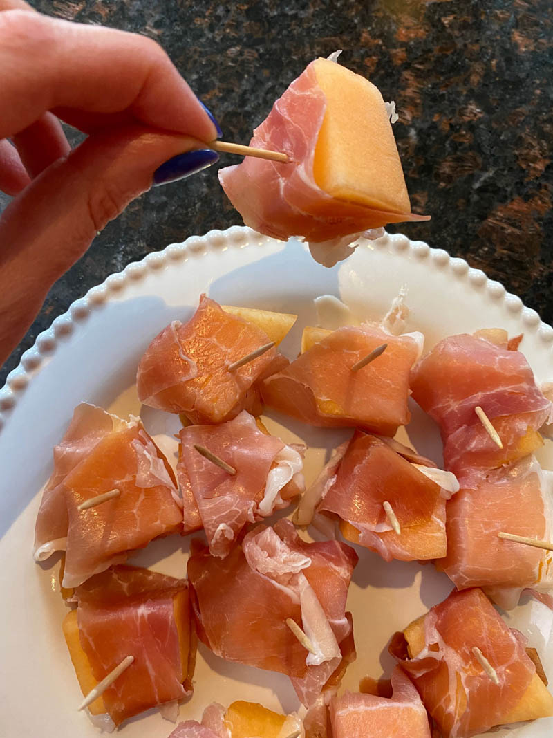 Prosciutto wrapped cantaloupe on a plate.