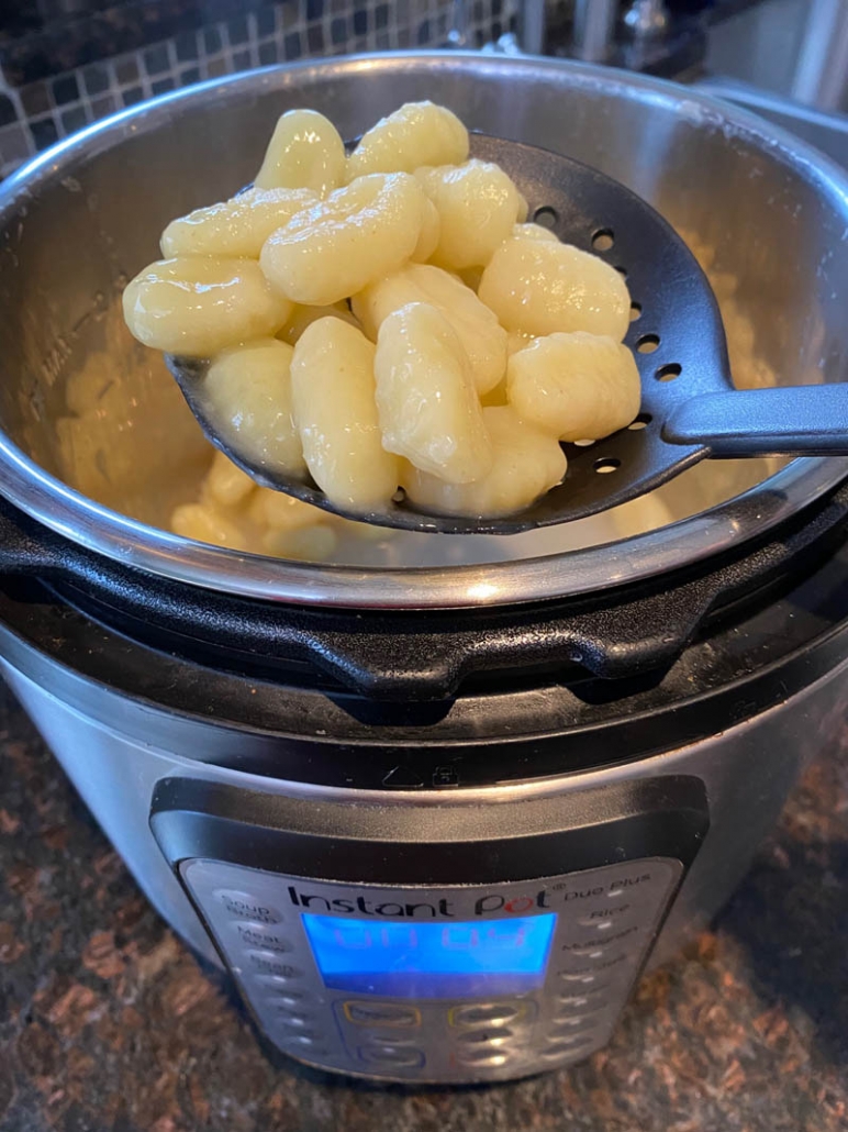 spoon holding cooked gnocchi above the instant pot