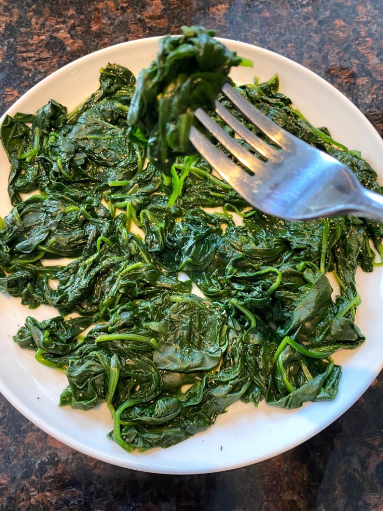 fork picking up instant pot cooked spinach from plate