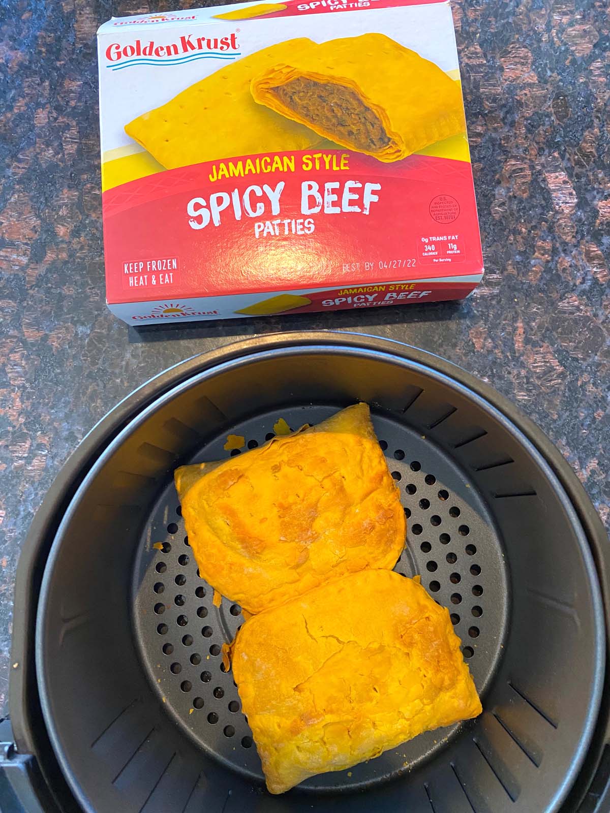 Cooked Jamaican beef patties in the air fryer with the box next to it.