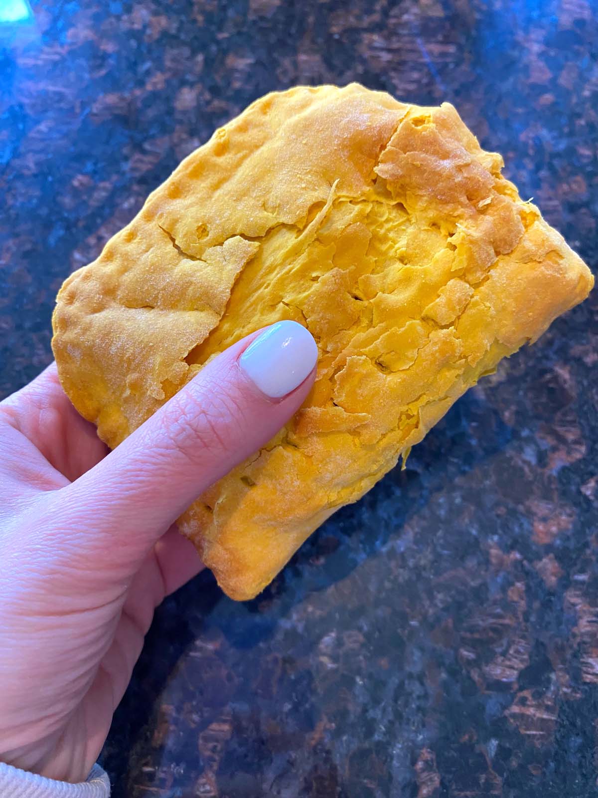 A cooked Jamaican beef patty being held up.