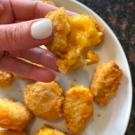 Cooked mac and cheese bites on a plate with one being held up.