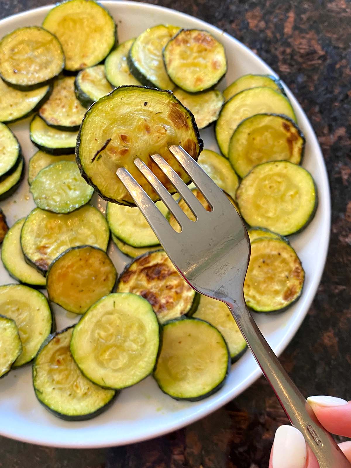 Plate of air fried roasted zucchini slices with a fork.