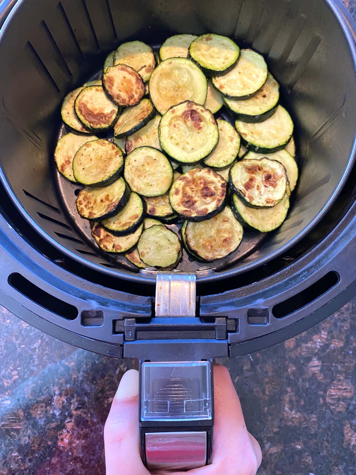 Air fryer roasted zucchini slices in the air fryer basket.