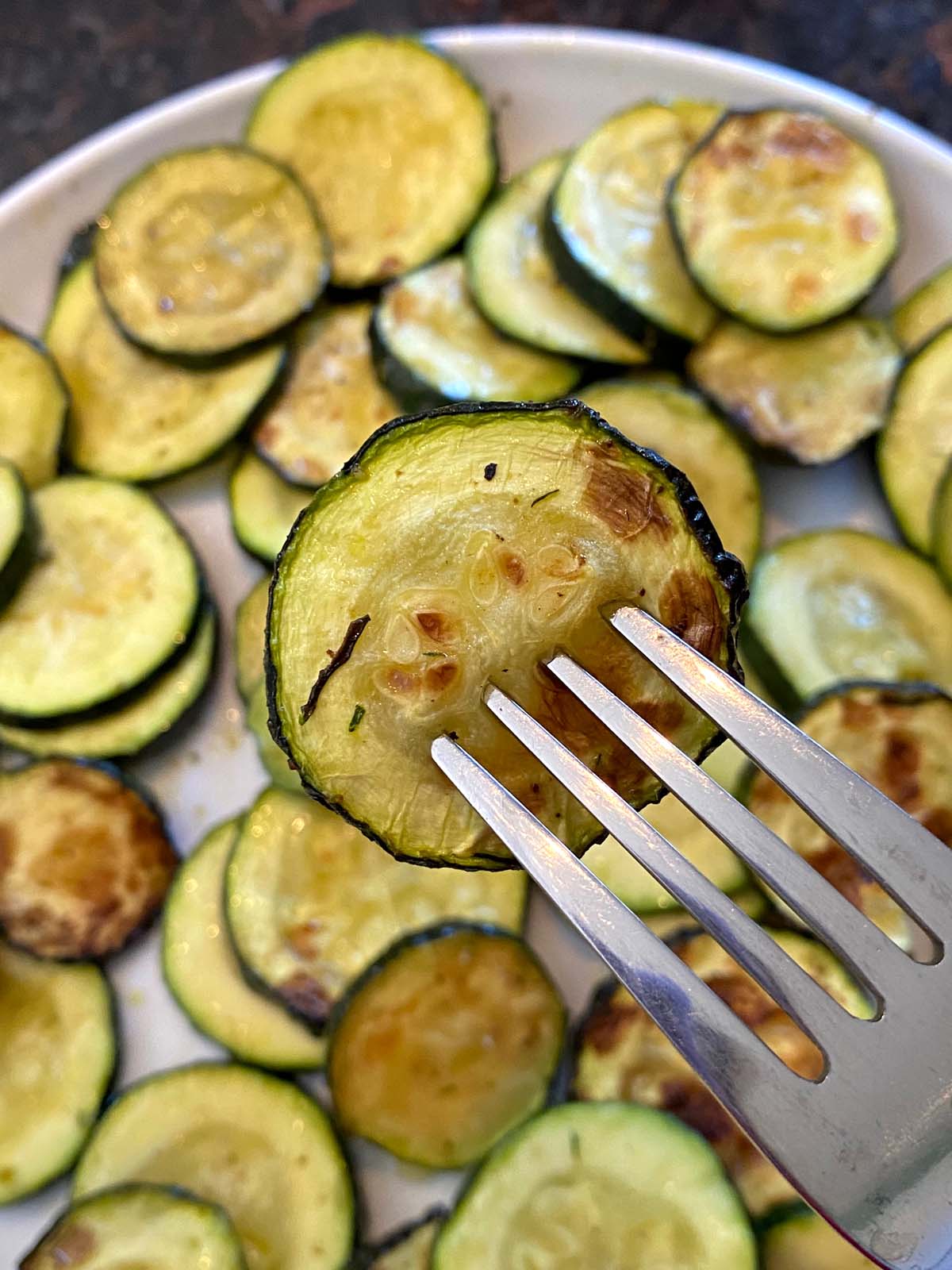 Air fried roasted zucchini slices with a fork.