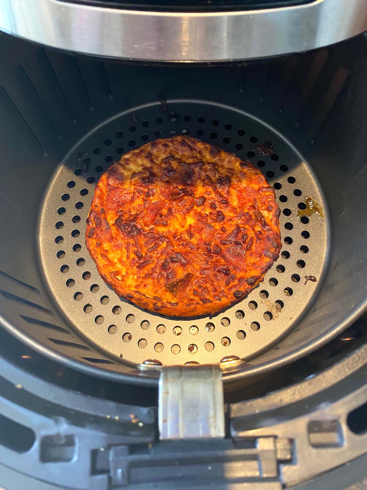 Single size deep dish frozen pizza in air fryer basket.