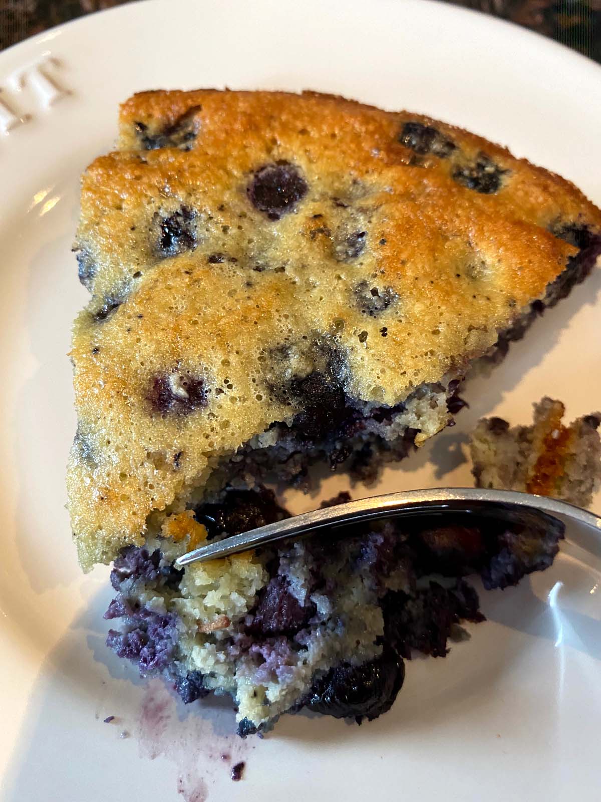 A slice of gluten free blueberry cake on a plate.