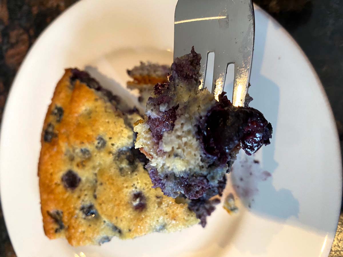 A slice of gluten free blueberry cake on a plate.