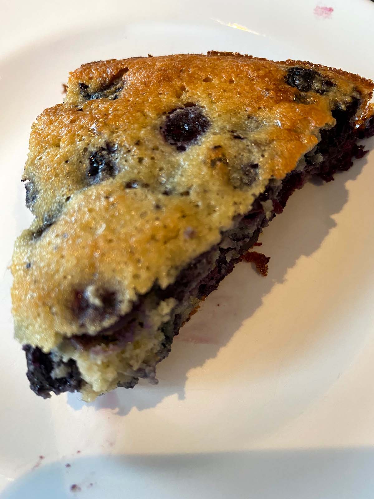 A slice of gluten free blueberry cake on a plate.