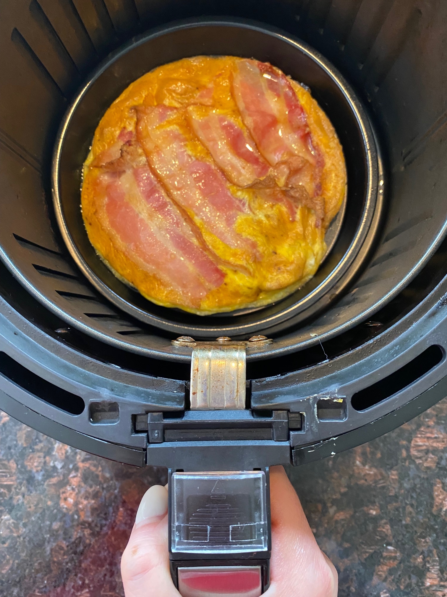 Cooked bacon and eggs in the air fryer basket.