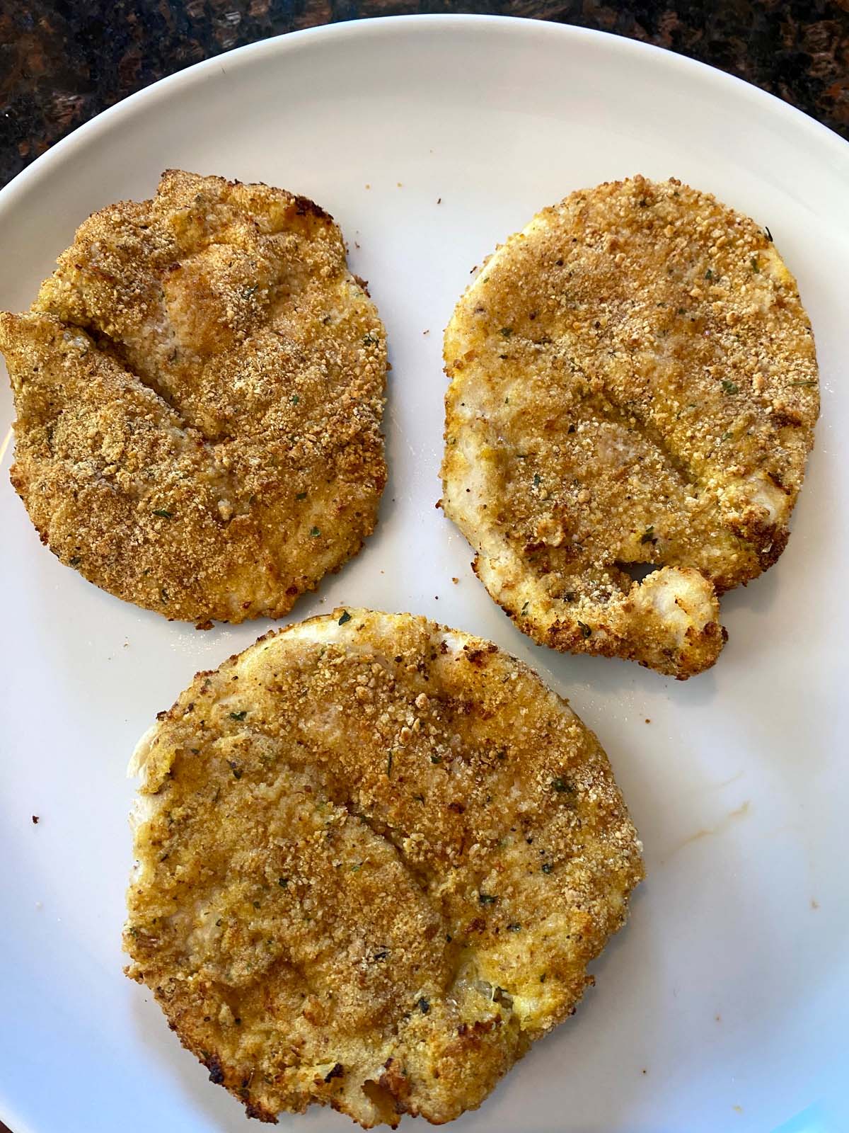 3 crispy turkey cutlets on white plate.