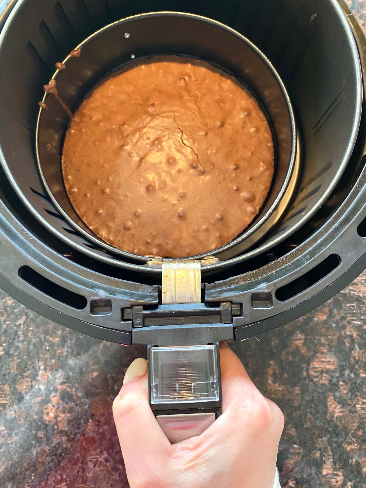 Brownie in a springform pan being removed from air fryer.