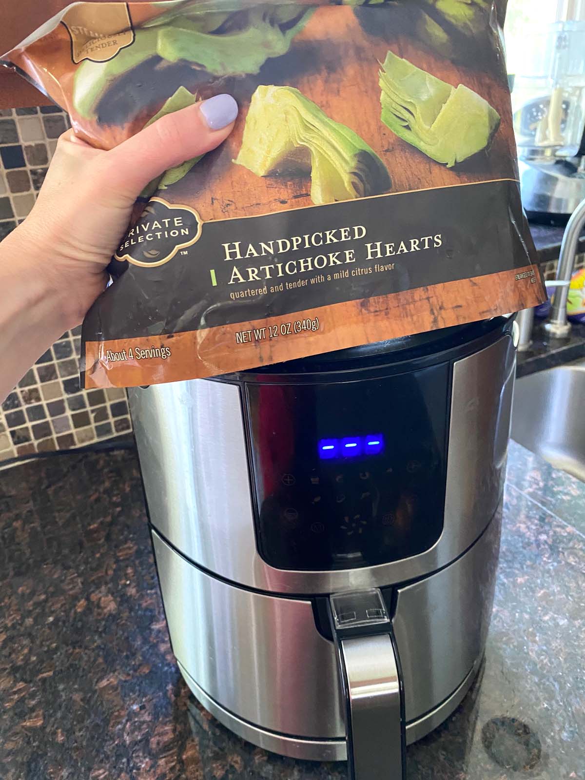 A bag of frozen artichoke hearts in front of an air fryer.