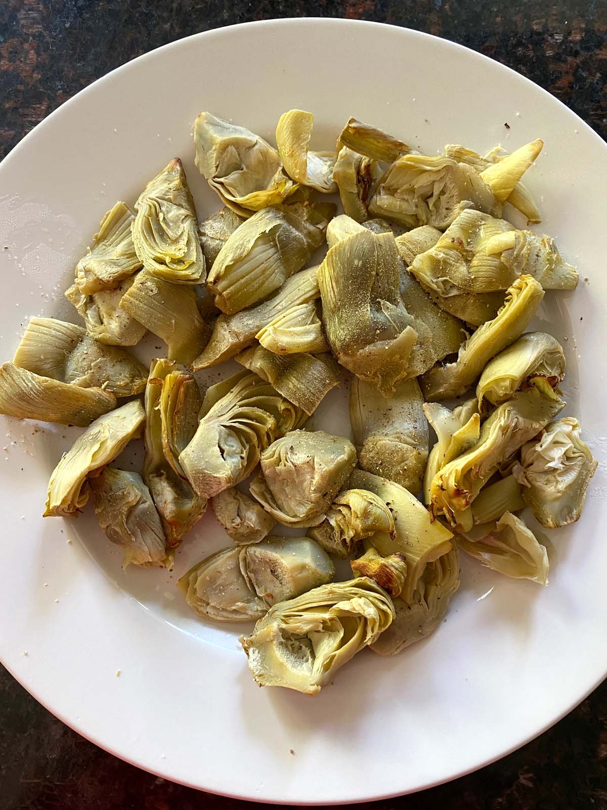 Cooked artichoke hearts on a white plate.