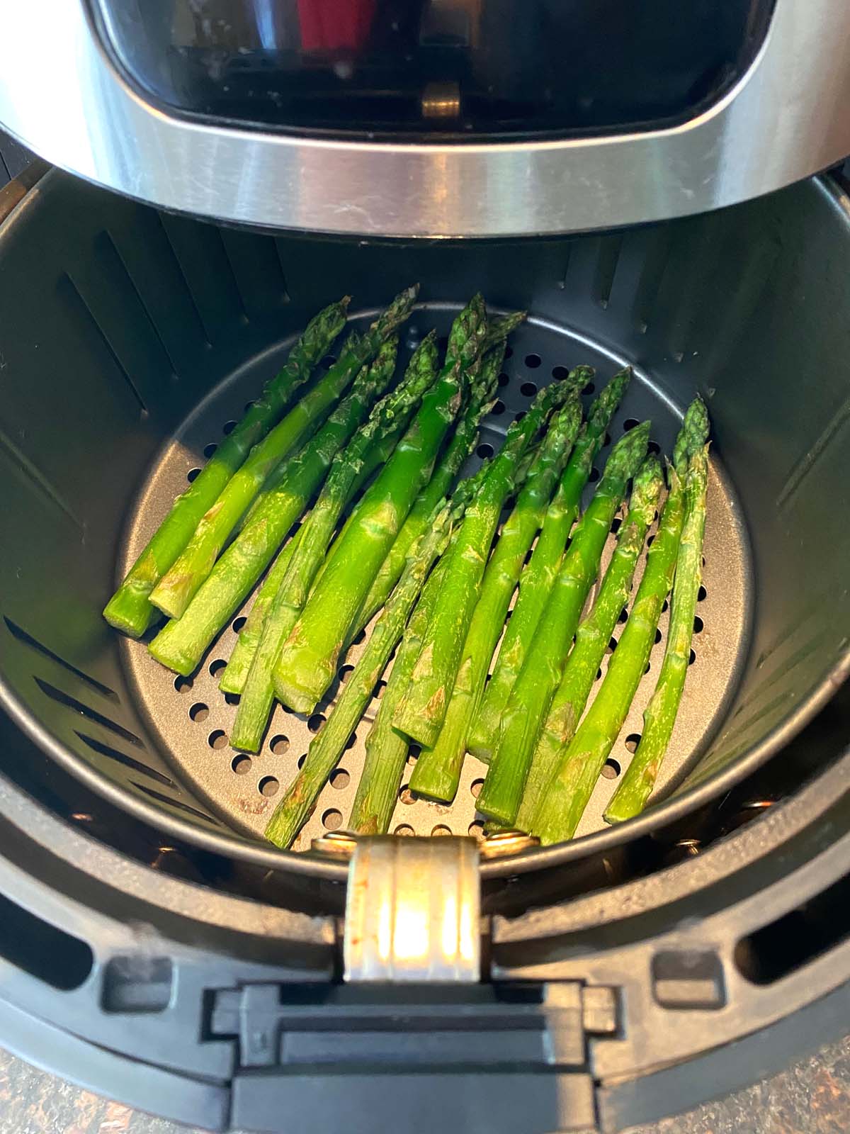 Cooked asparagus in an air fryer.