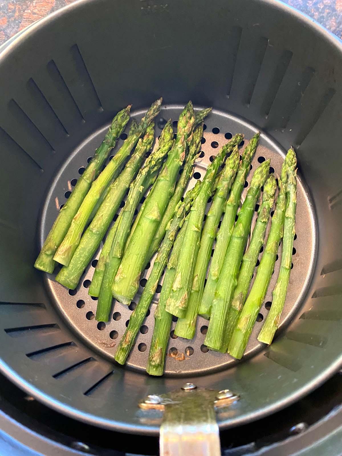 Cooked asparagus in an air fryer.