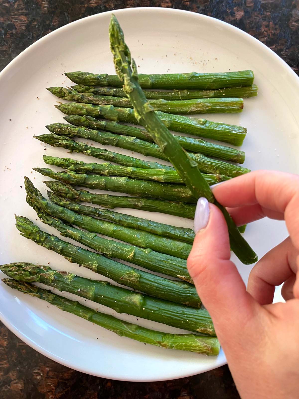 Cooked asparagus on a white plate.