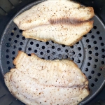 Cooked tilapia filets in an air fryer.