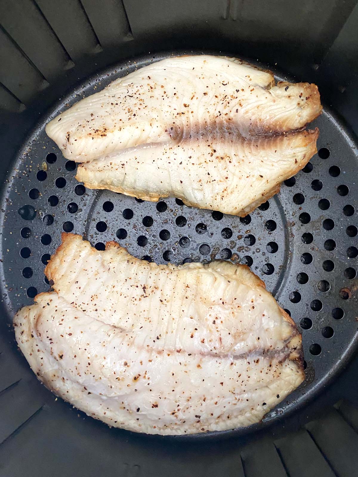 Cooked tilapia filets in an air fryer.