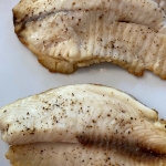 Cooked tilapia filets on a plate.
