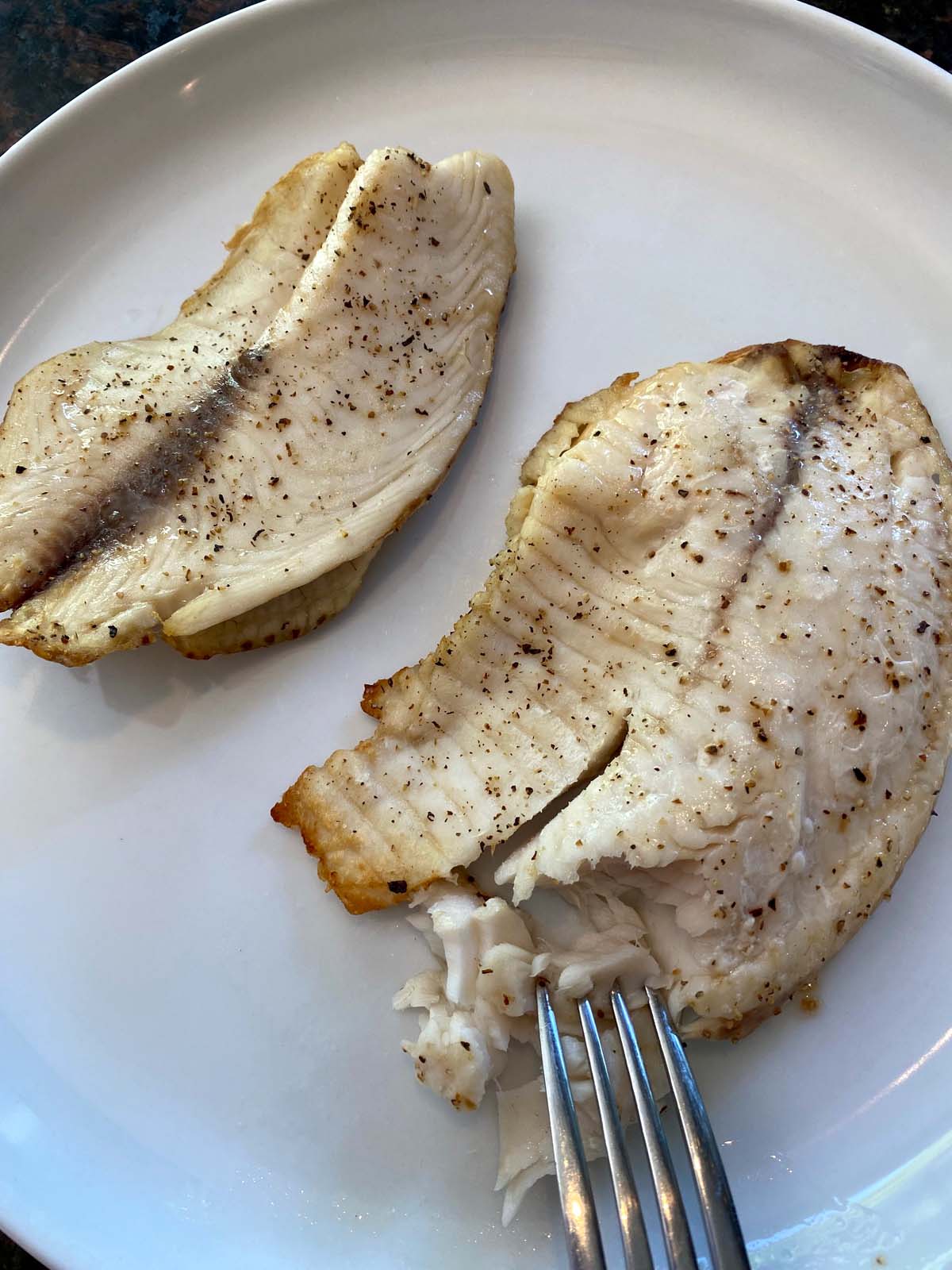 Cooked tilapia filets on a plate.