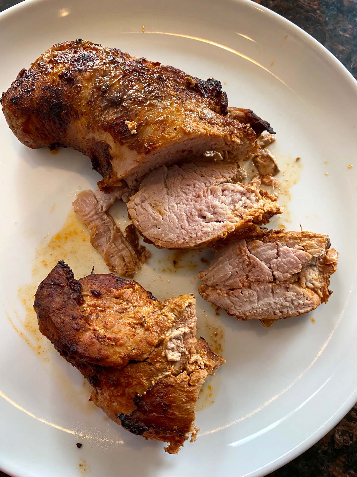 Pork tenderloin with a crispy crust and juicy inside with a few slices cut.