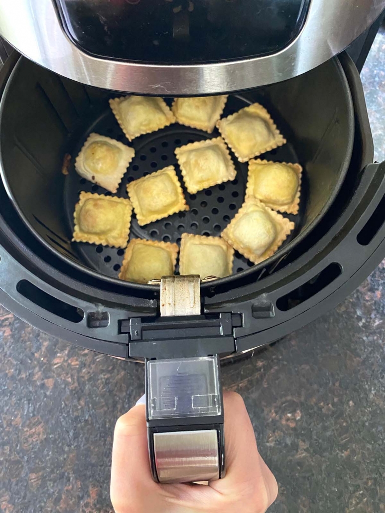 air fryer opened to show frozen ravioli inside