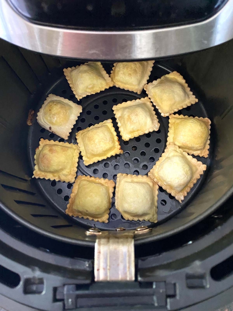 air fryer opened to show toasted ravioli