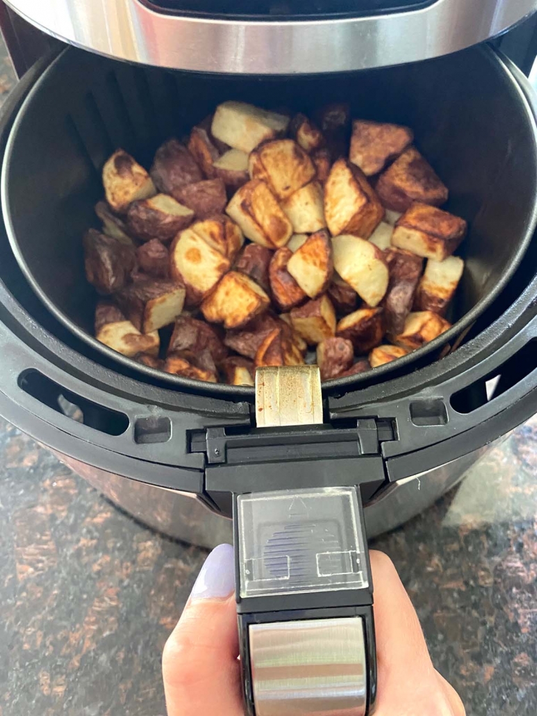 air fryer basket opened to show cooked potatoes