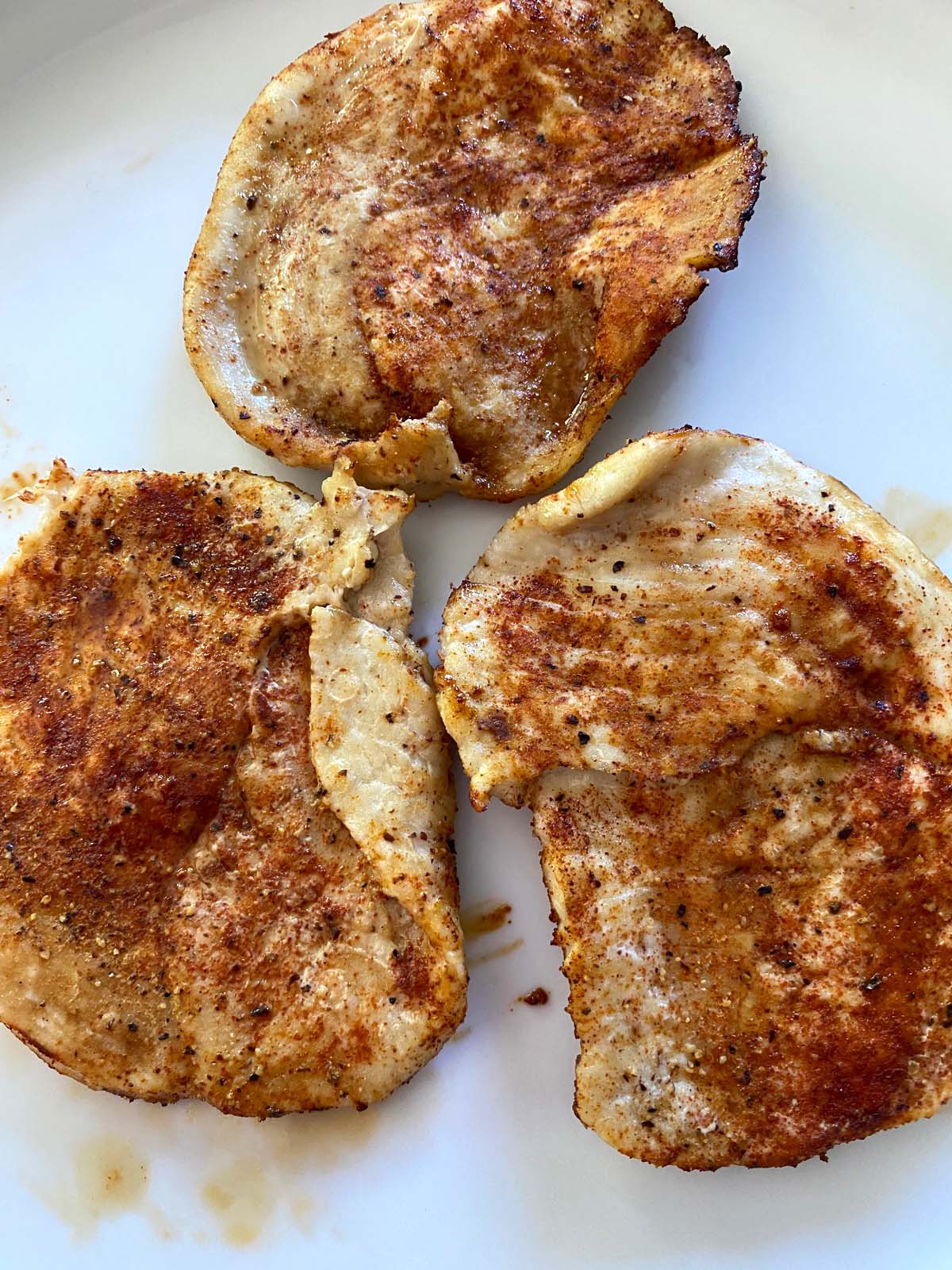 3 pieces of seasoned turkey breast cutlets on large white plate.