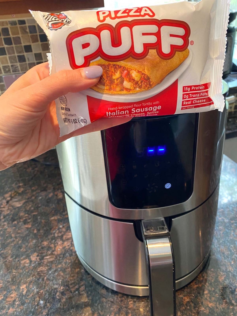 hand holding air fryer pizza puff package in front of the air fryer