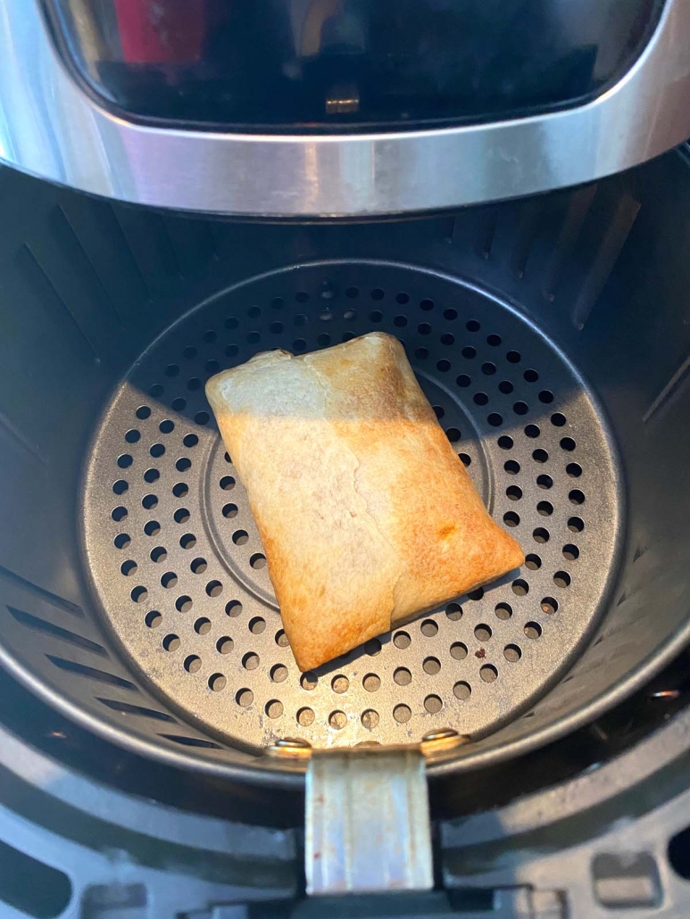 overhead view of frozen pizza puff inside the air fryer basket