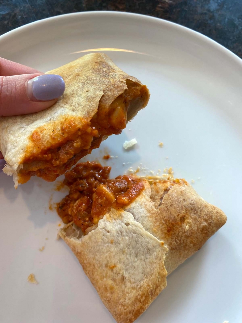 hand holding torn open pizza puff half on a plate