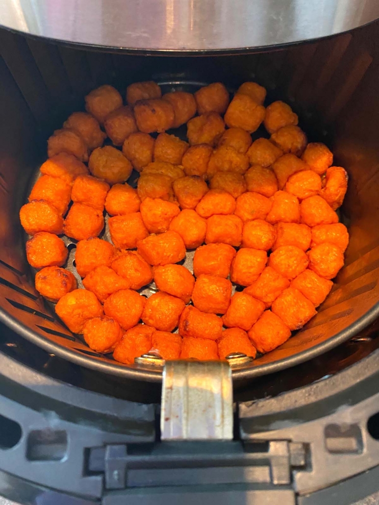 view of sweet potato puffs in the air fryer before cooking
