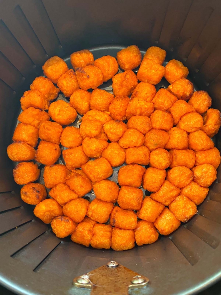 close up overhead view of frozen sweet potato puffs in the air fryer