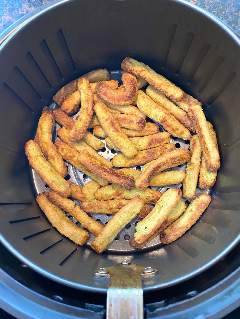 overhead view of air fried zucchini fries in air fryer basket