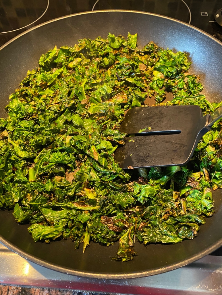 fresh kale in pan cooking with a spatula stirring it