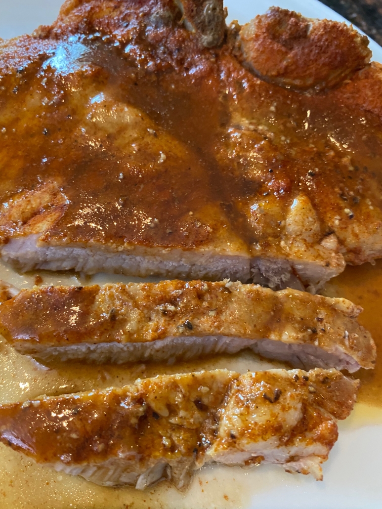 gravy topped pork chops sliced on a plate