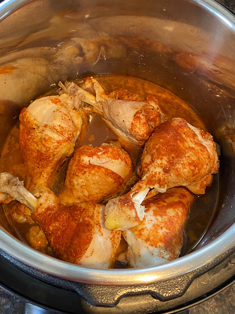 Close up of chicken drumsticks in a pressure cooker.