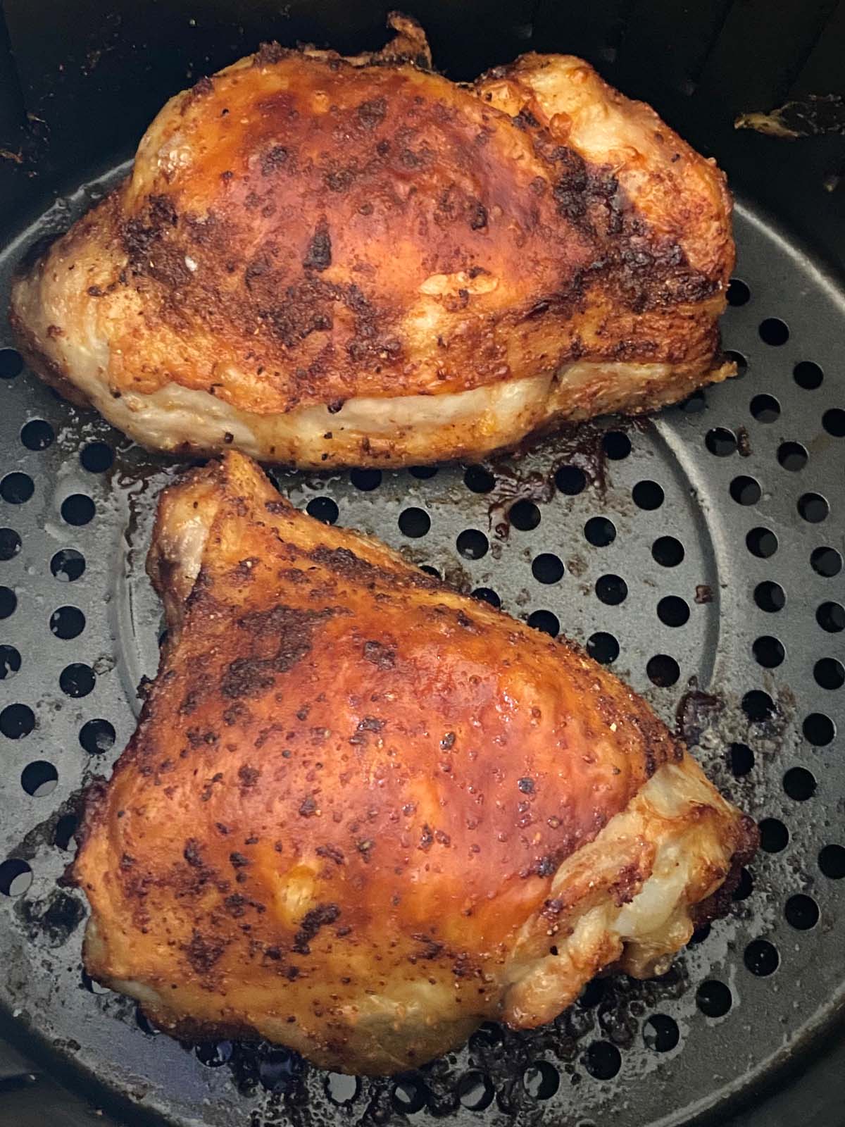 Cooked chicken thighs in an air fryer.