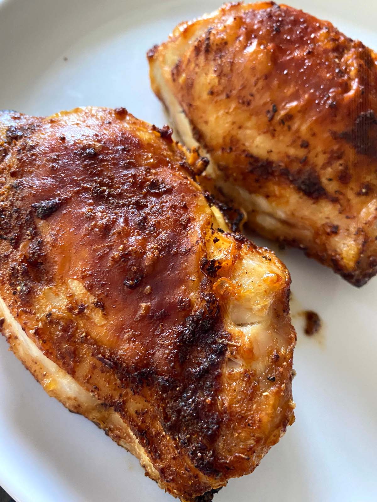 Cooked chicken thighs on a white plate.