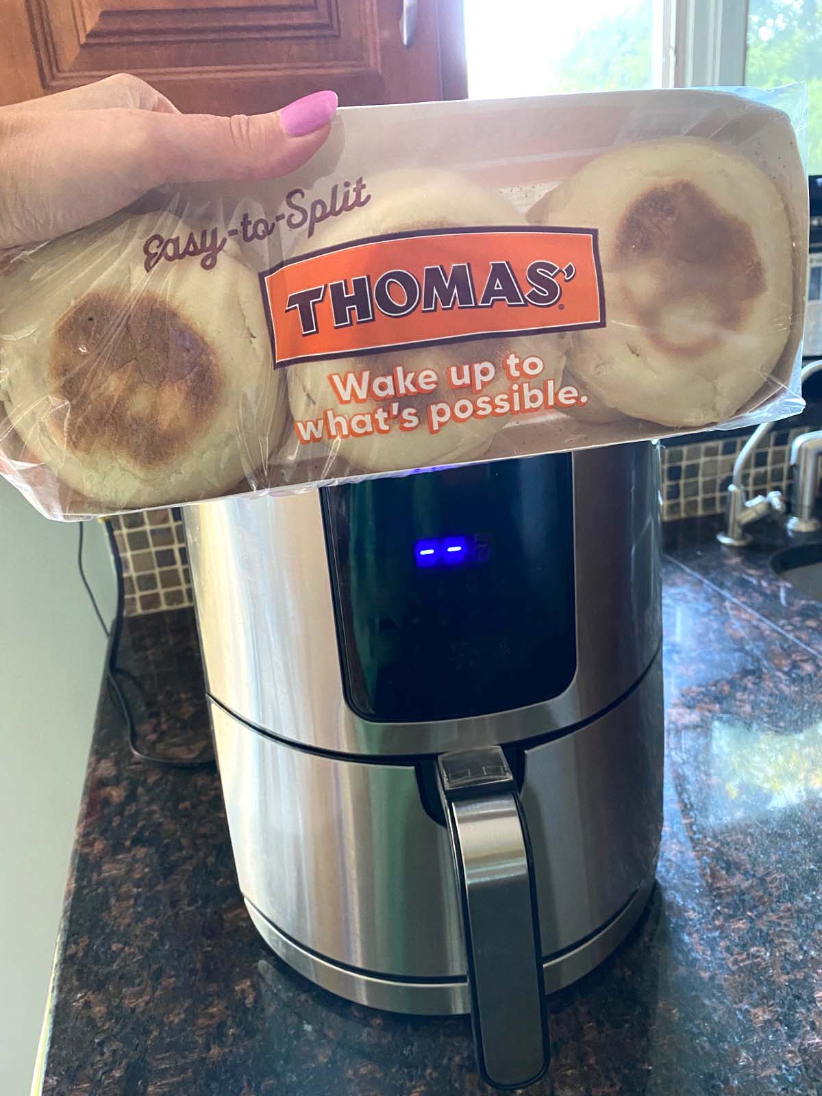 Package of english muffins in front of an air fryer.