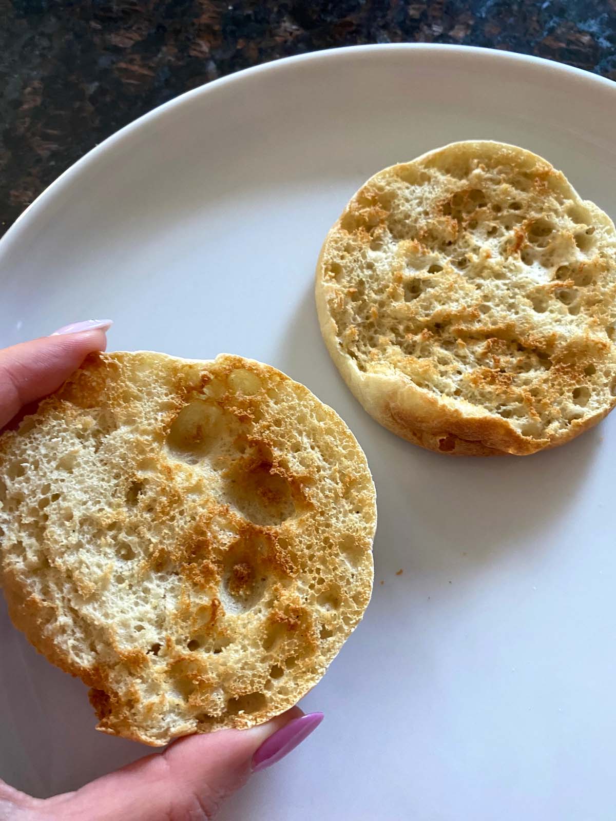 Toasted english muffin on a white plate.