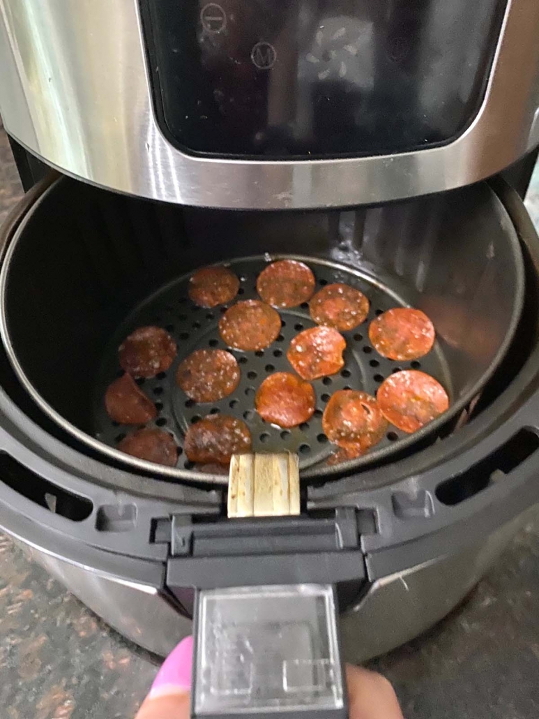 opening air fryer to show cooked pepperoni chips inside