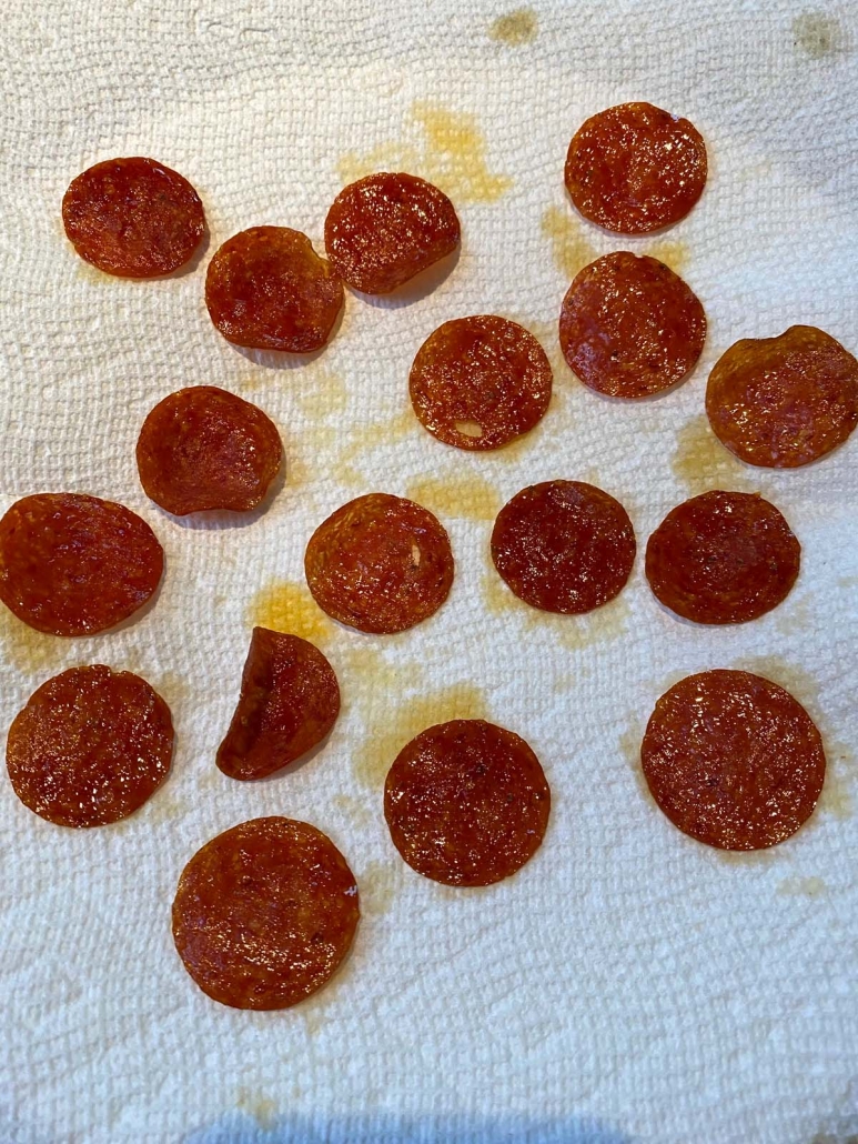 cooked pepperoni slices draining on a paper towel