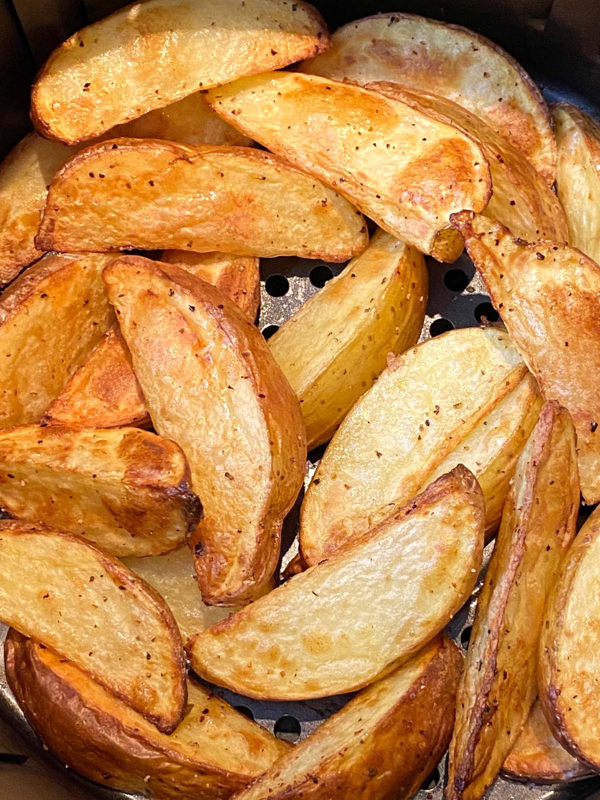 Cooked potato wedges in an air fryer.