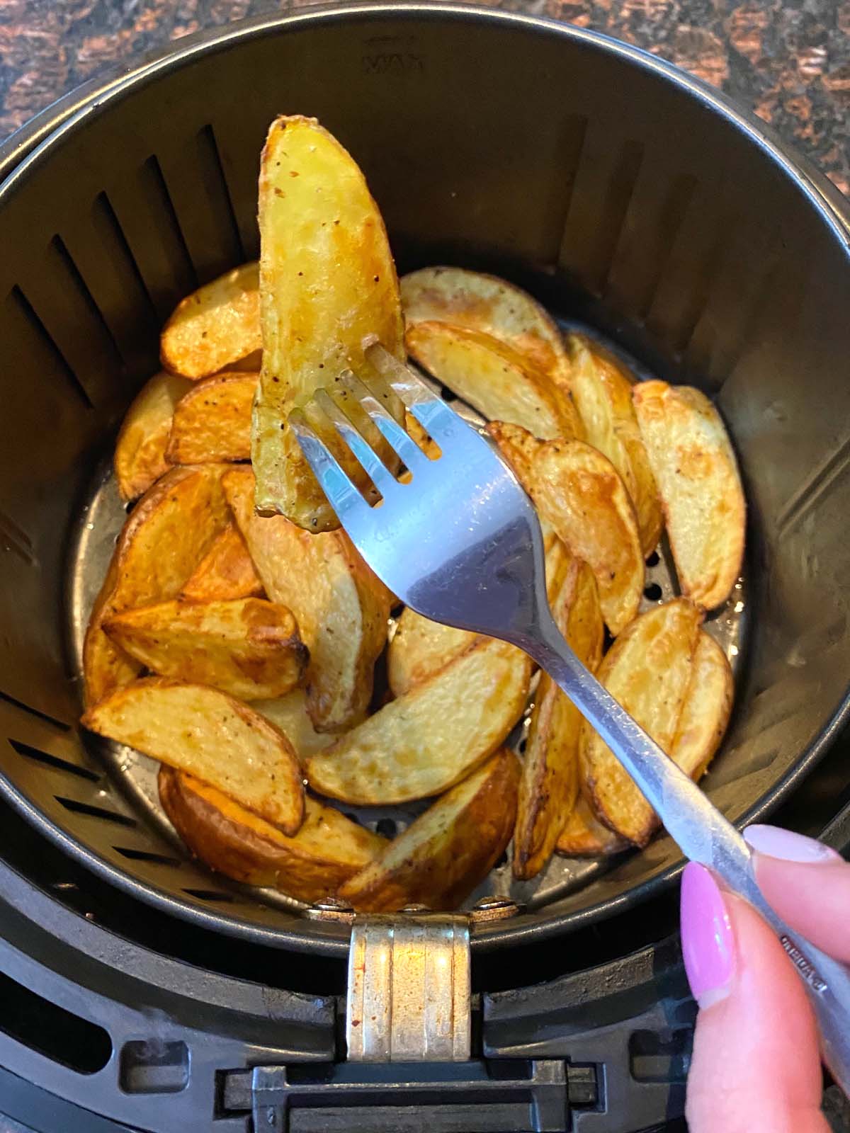 Cooked potato wedges in an air fryer.