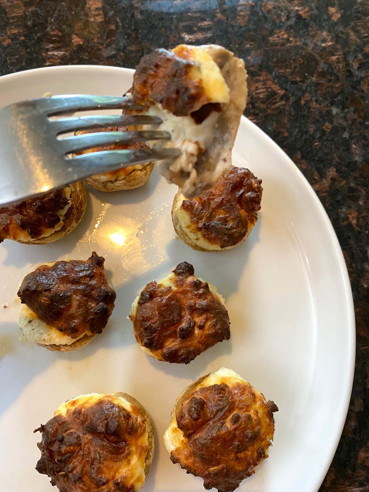 Cooked stuffed mushrooms on a white plate.